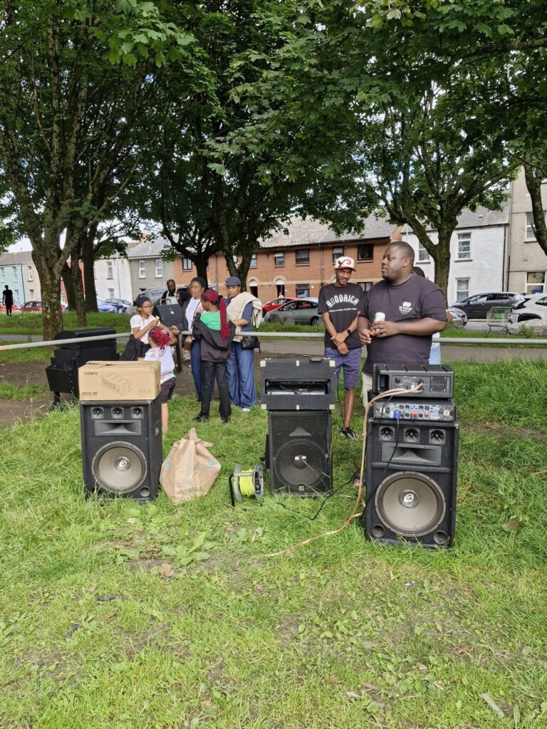 Volunteers setting up the sound system on the field at the ZNVA Refugee Week family fun day, June 2026
