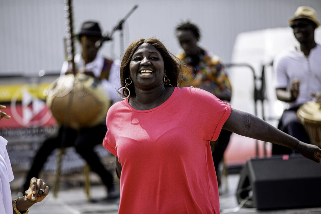 A woman dances with her arms outstretched as drummers play behind her at ZNVA's Africa Day celebration in Newport